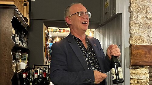 Daniel O'Keefe wielding a bottle of wine